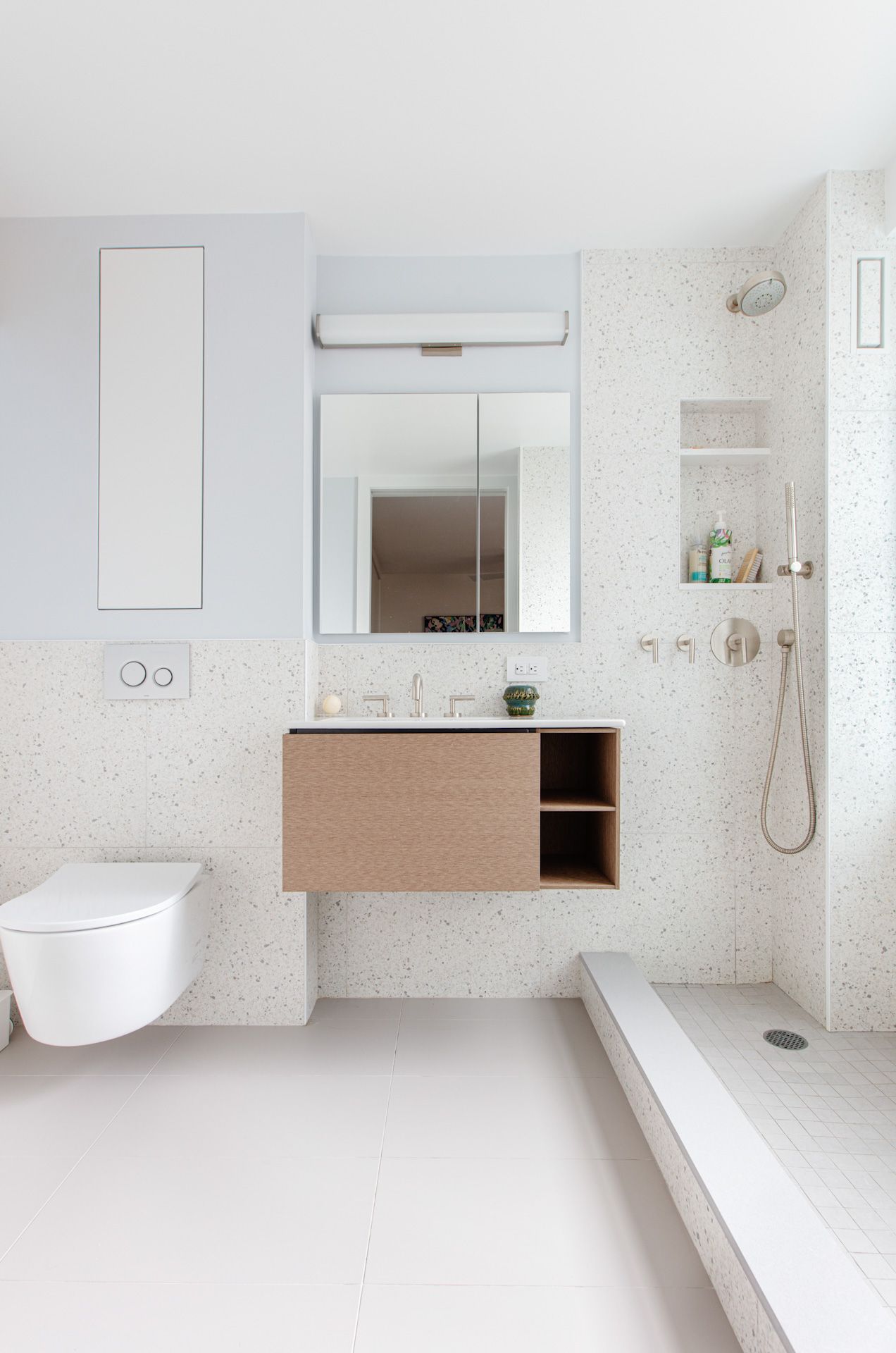 A bathroom with a toilet, sink, mirror and shower.