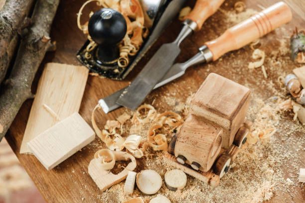 Wooden toy car and heart, woodworking tools, wood shavings on a wooden surface.