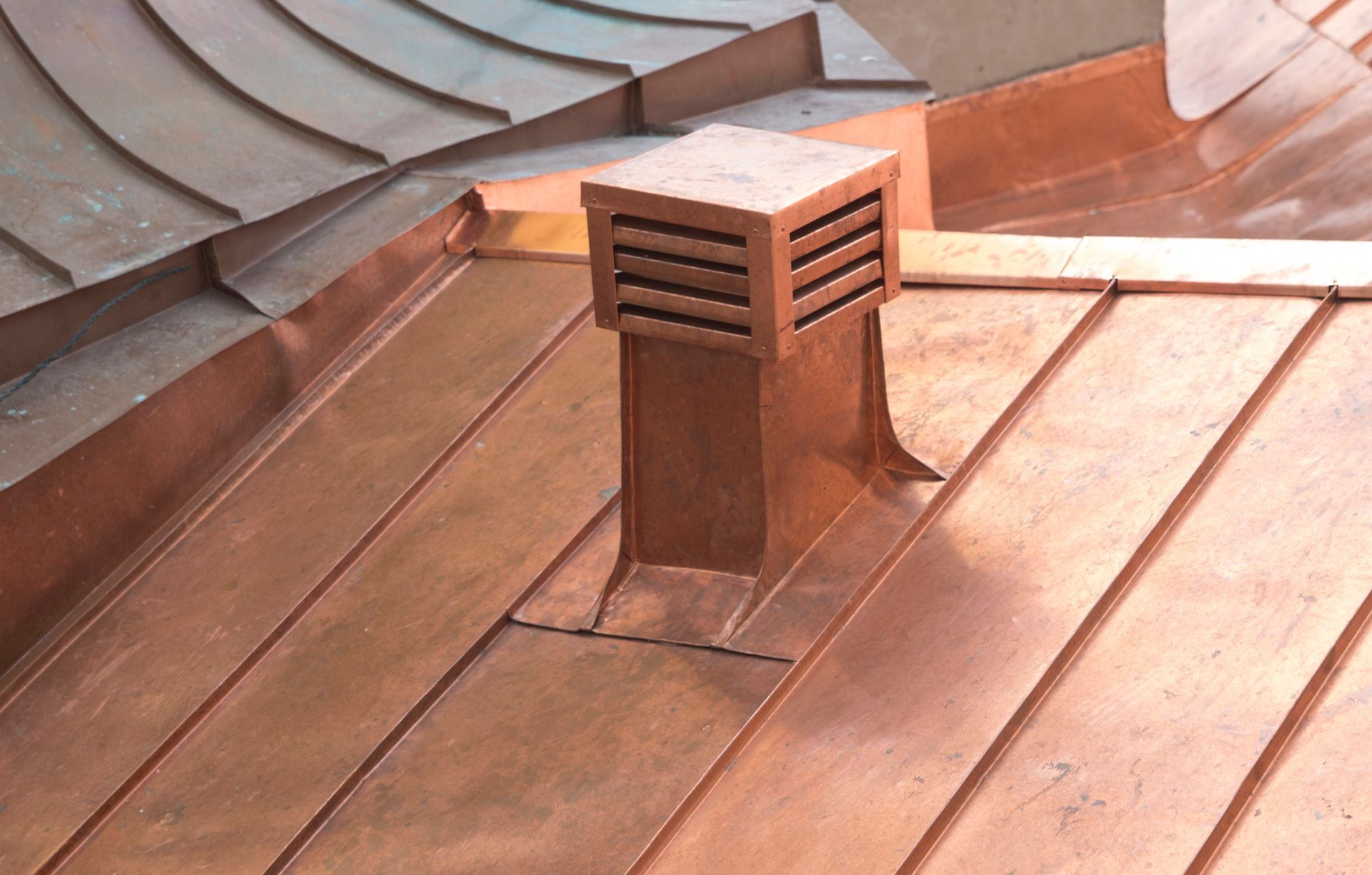 Copper roof with a square vent stack and a curved roof edge.