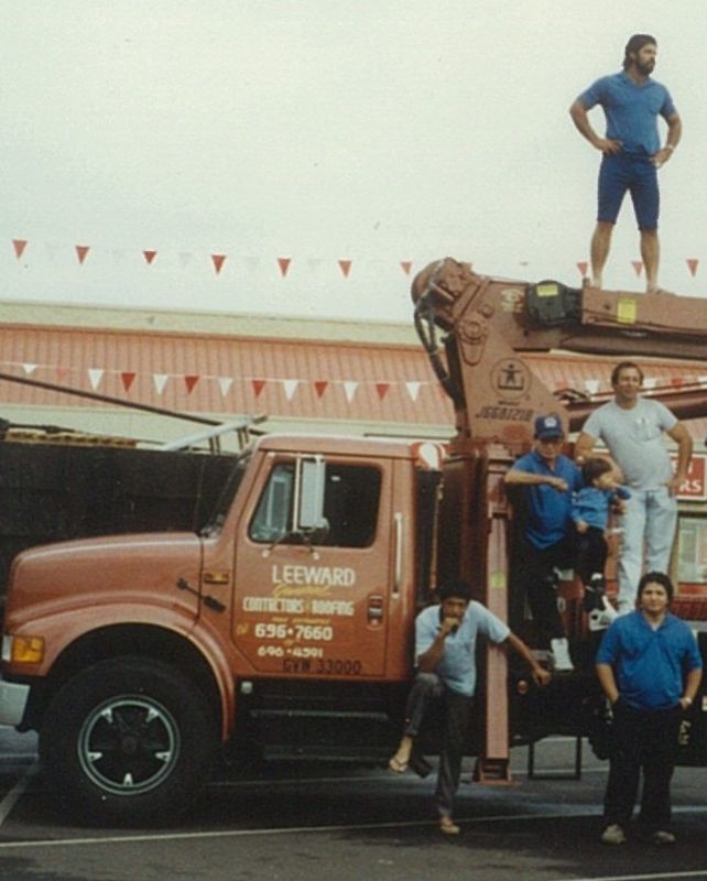 A group of men standing on top of a leonard truck