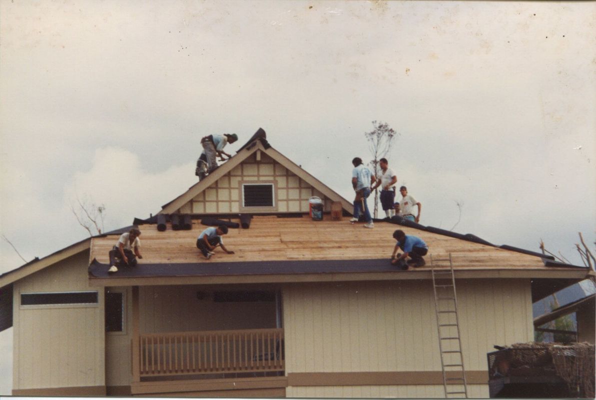 A group of people are working on the roof of a house