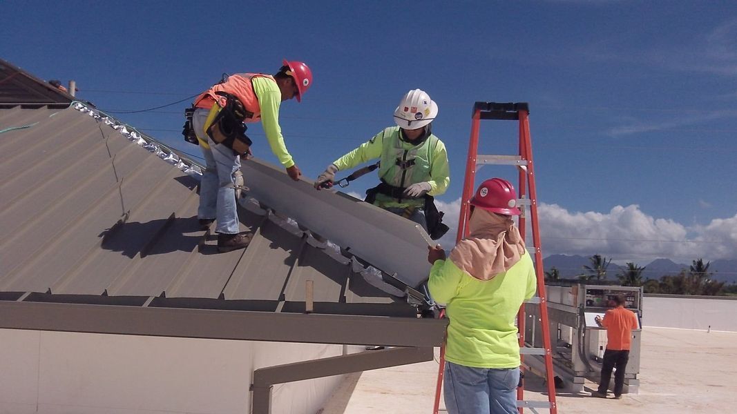 A group of construction workers are working on a roof.