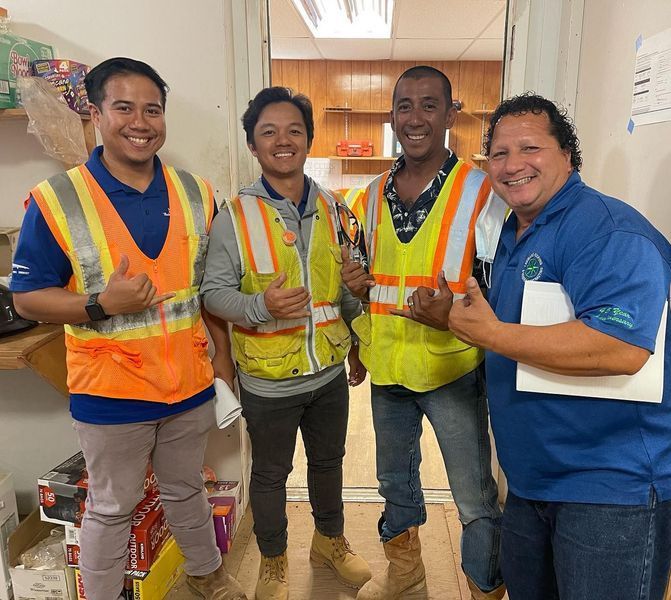 A group of men wearing safety vests and giving a thumbs up