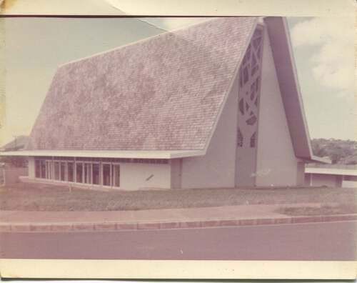 A black and white photo of a church with a triangle shaped roof.
