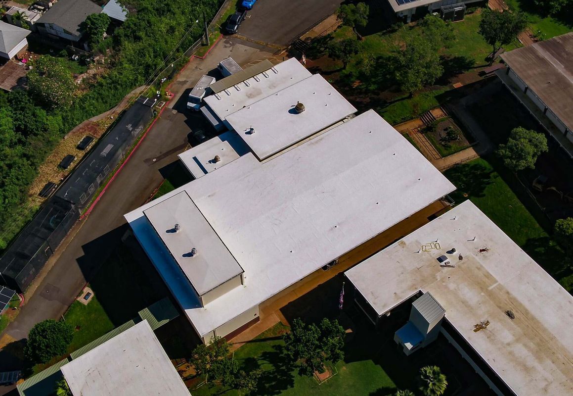 An aerial view of a building with a white roof