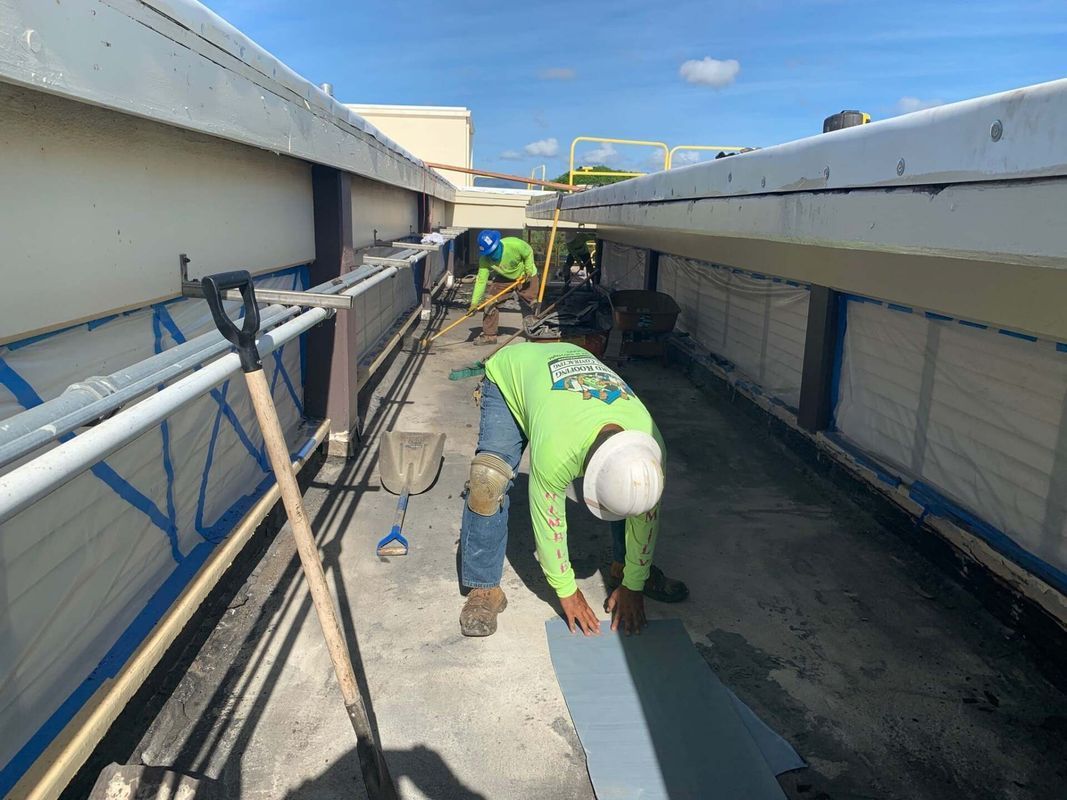 A man in a green shirt and hard hat is working on a roof.