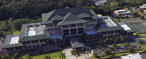 An aerial view of a large building surrounded by palm trees.