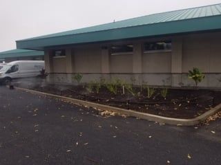 A white van is parked in front of a building with a green roof.
