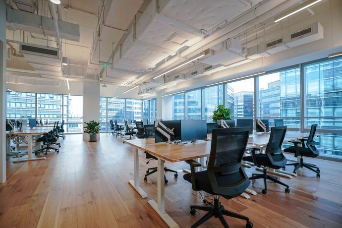 An empty office with tables and chairs and lots of windows.