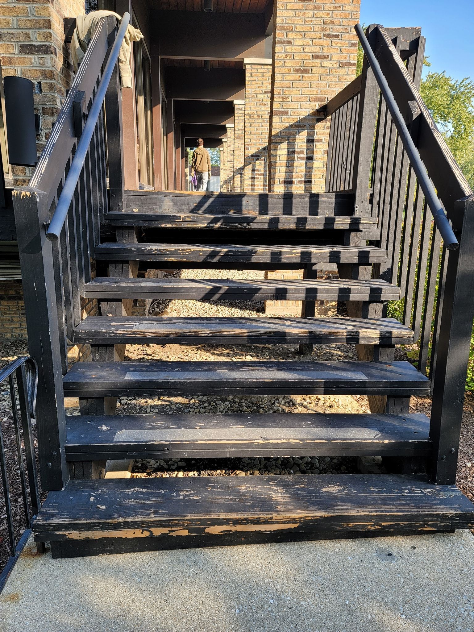 Black, weathered wooden outdoor staircase leading upward; building exterior in background.