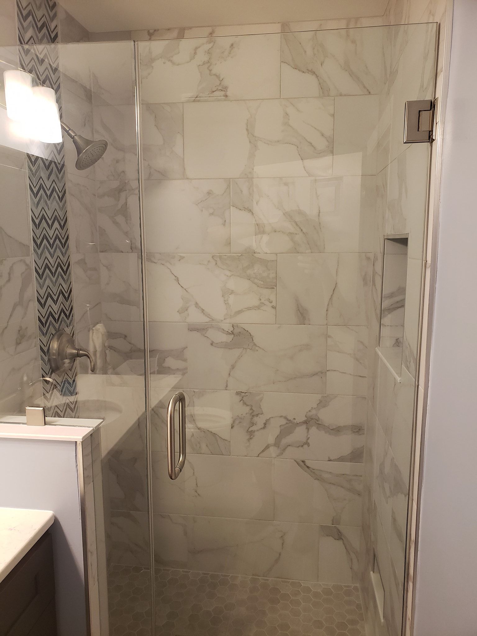 Modern bathroom with marble tile walls and a glass shower door.