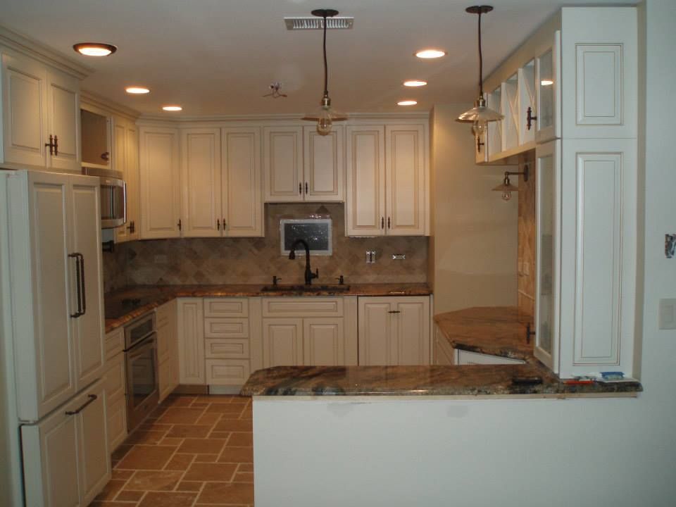 Cream-colored kitchen with granite countertops, tiled floor, and overhead lighting. Cabinets and appliances are white.