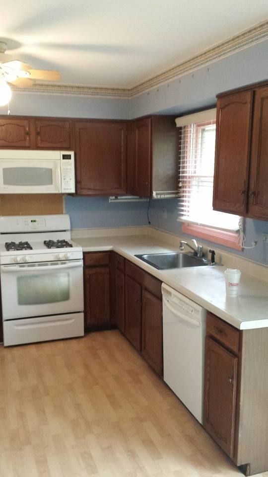 Kitchen with brown cabinets, white appliances, and light-colored countertops and flooring.