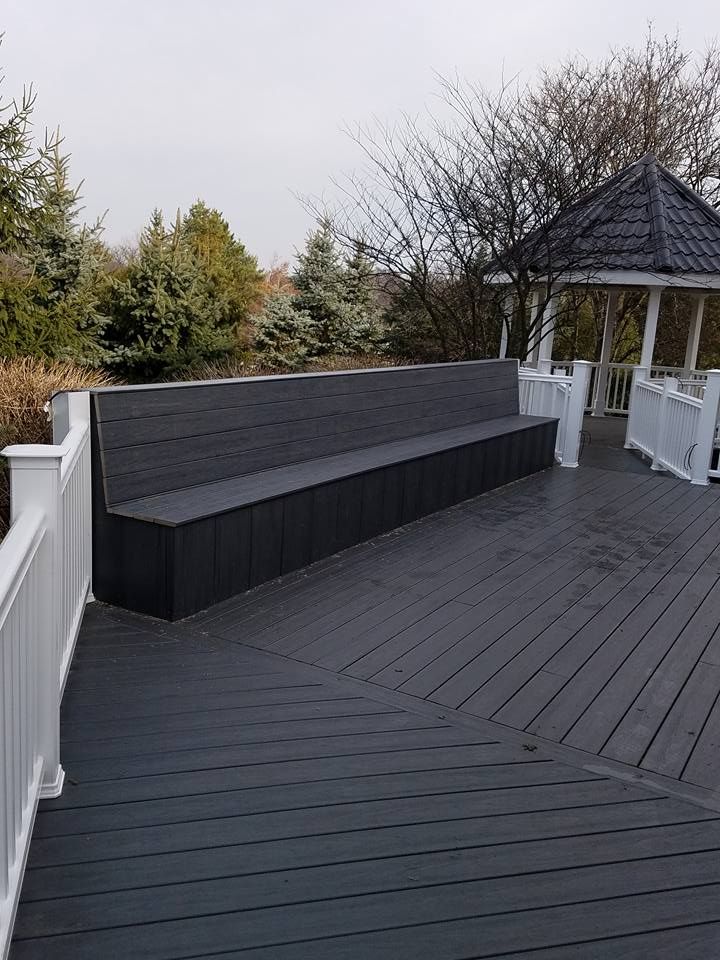 Dark gray deck with built-in bench and white railing, near a gazebo.