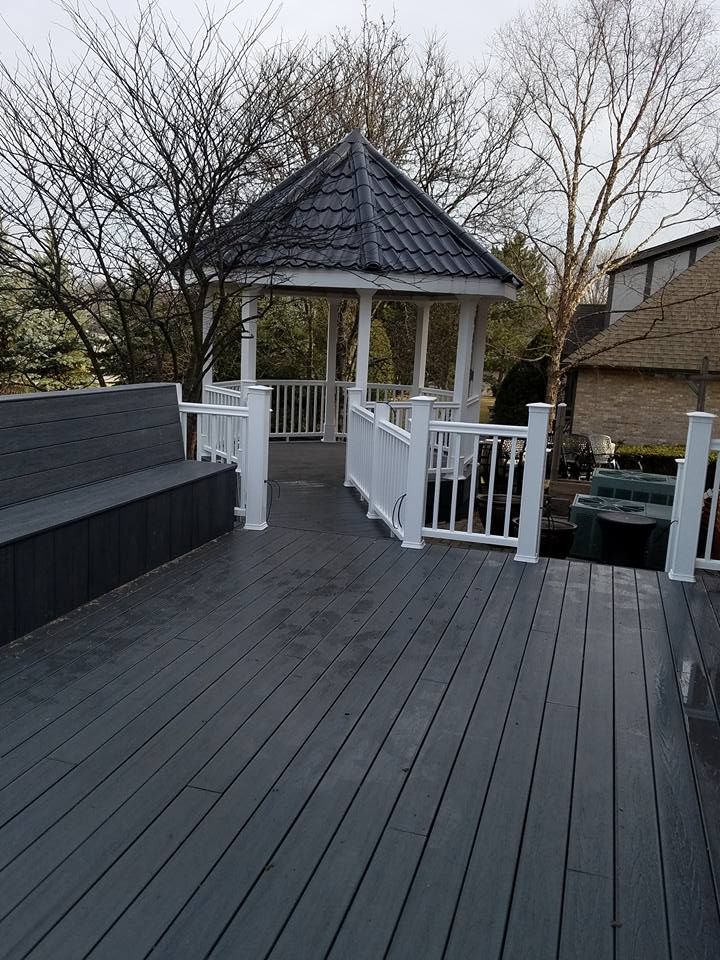 Grey deck with white railing leads to a gazebo with a dark roof.