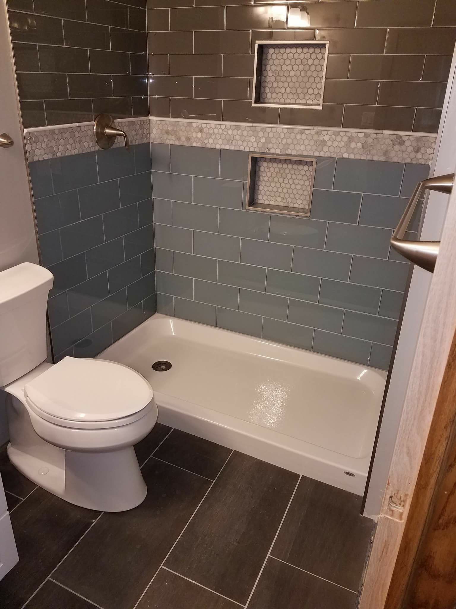 Bathroom with a tiled shower, toilet, and dark floor tiles.