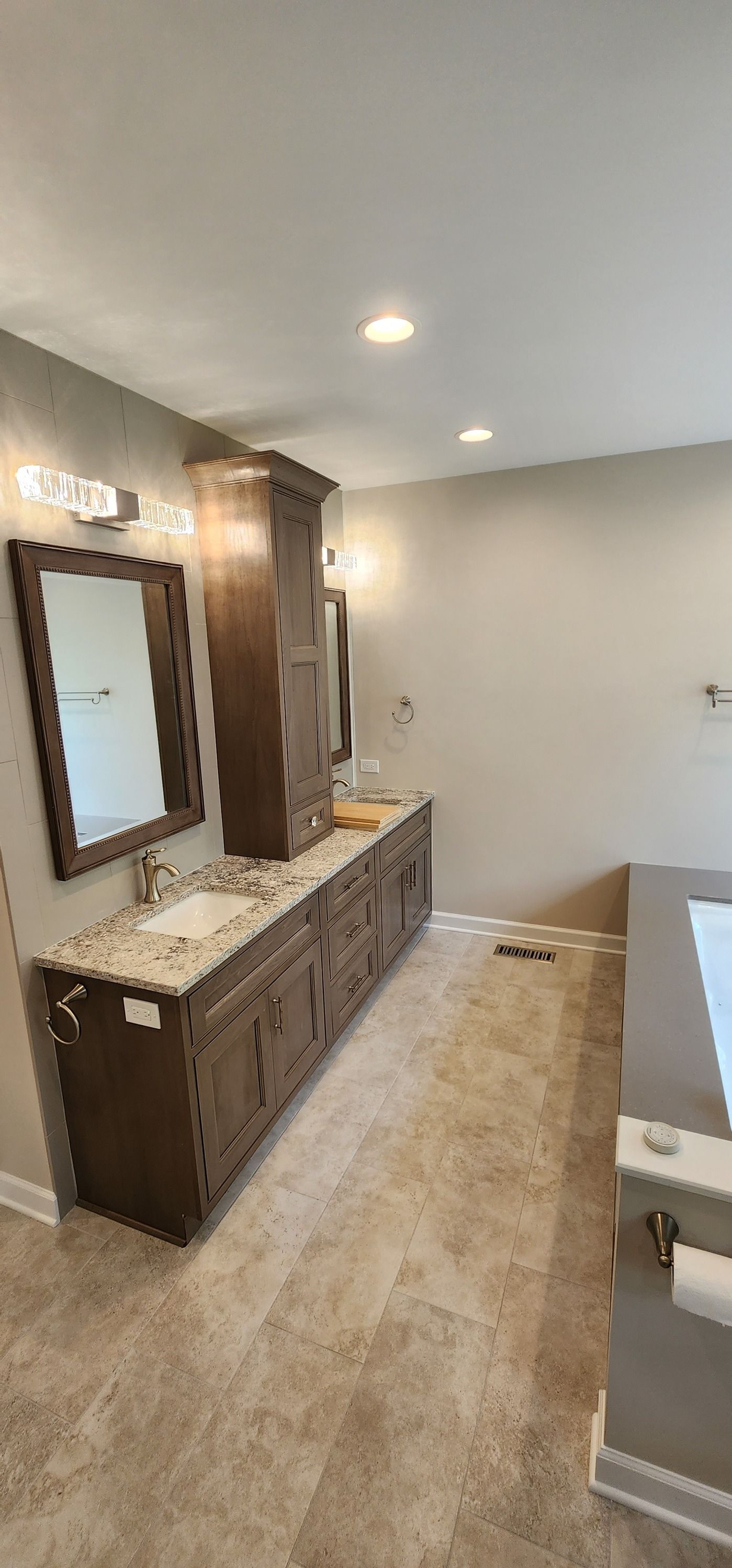 Bathroom with dark wood vanity, tall cabinet, stone countertop, and tan carpet.