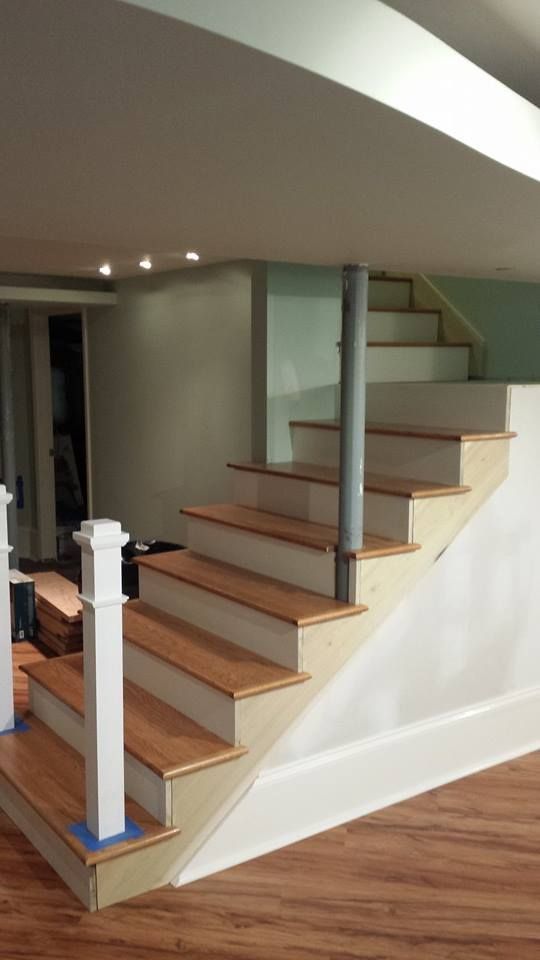 Staircase with wooden steps and white risers, a support beam, and painted walls.