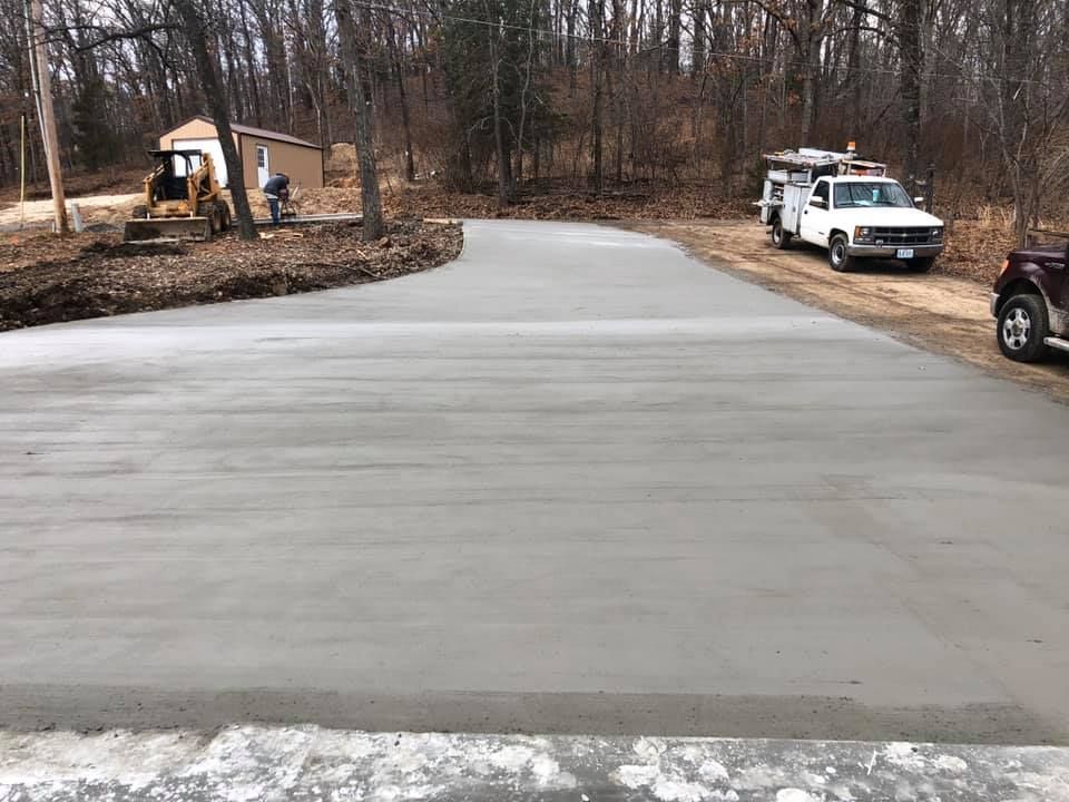 Freshly poured concrete driveway with work trucks in the background
