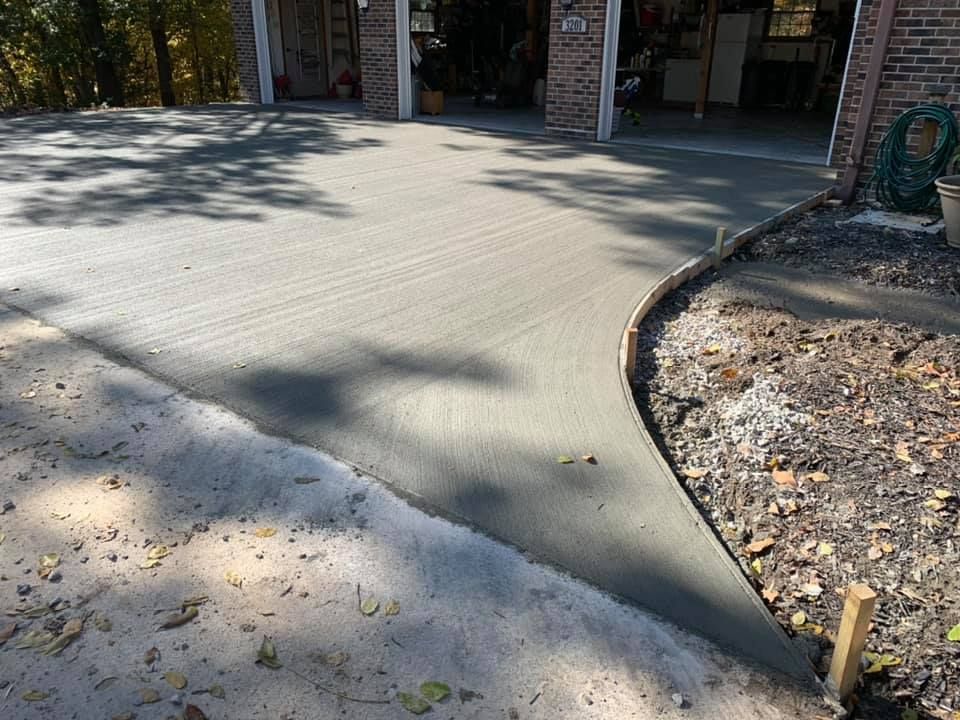 Freshly poured concrete driveway with work trucks in the background