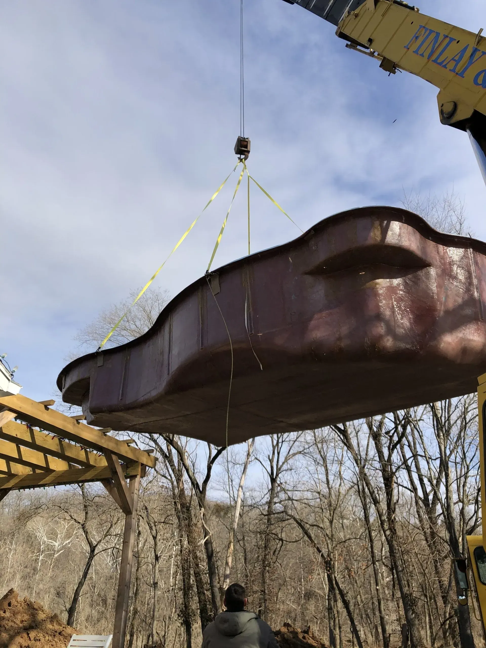 large fiberglass pool being lowered into the ground by a crane