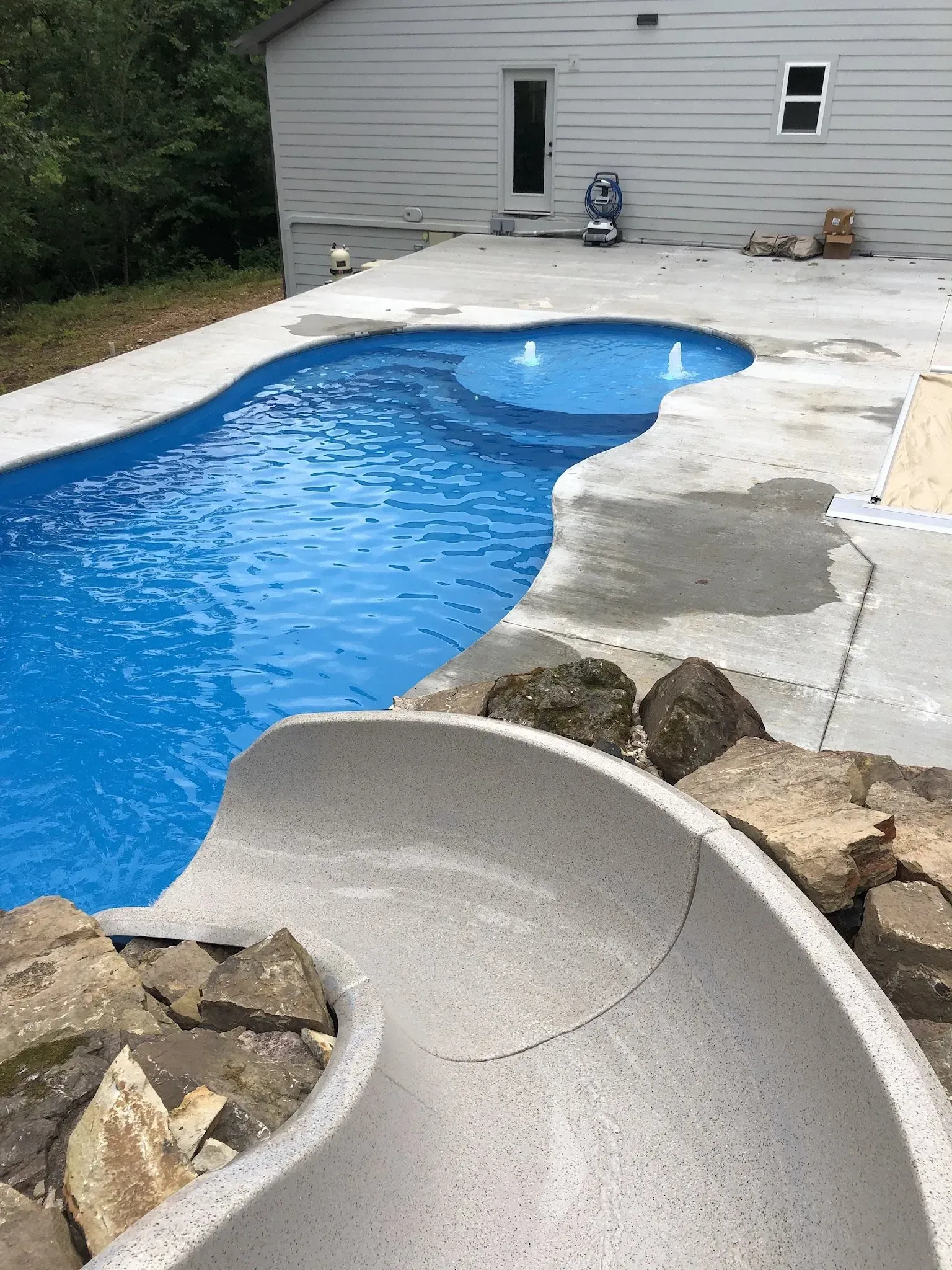 freeform pool with water features and a slide. View is from the top of the slide
