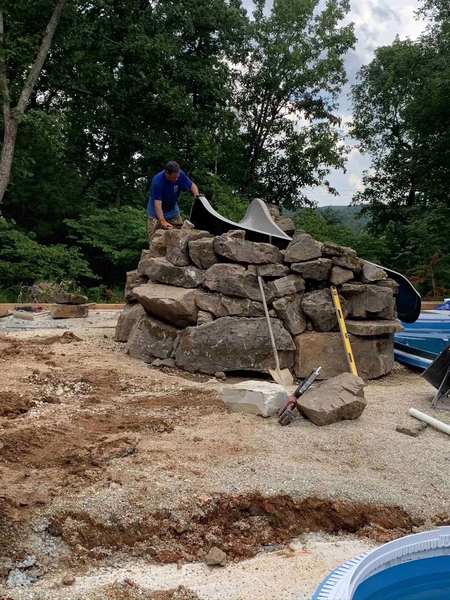 Employee building rock wall to support water slide 