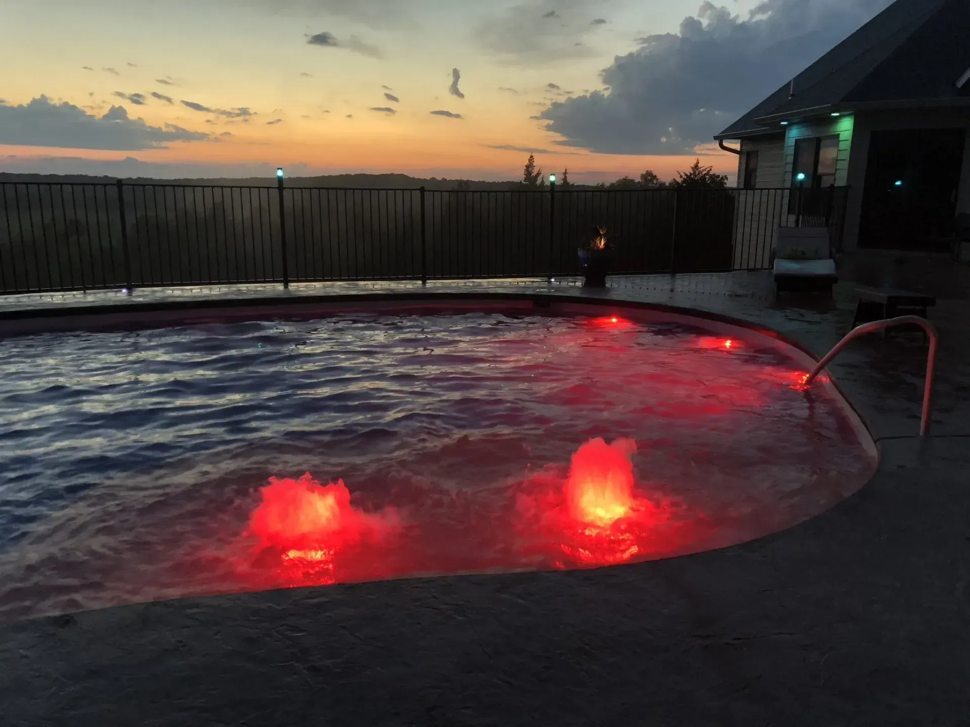 small pool at sunset with lit up water feature