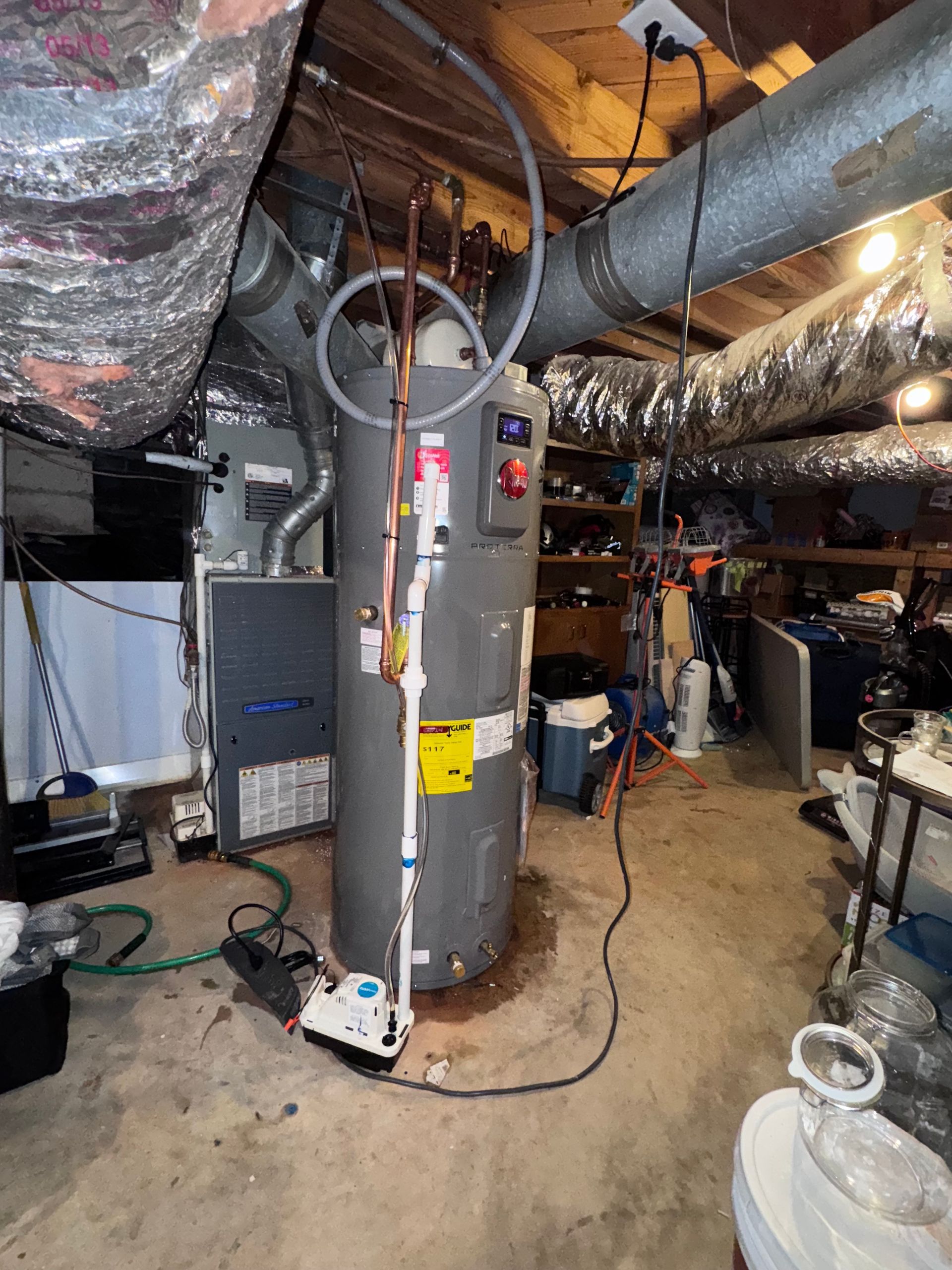 Water heater and furnace in a basement setting, with ductwork overhead.