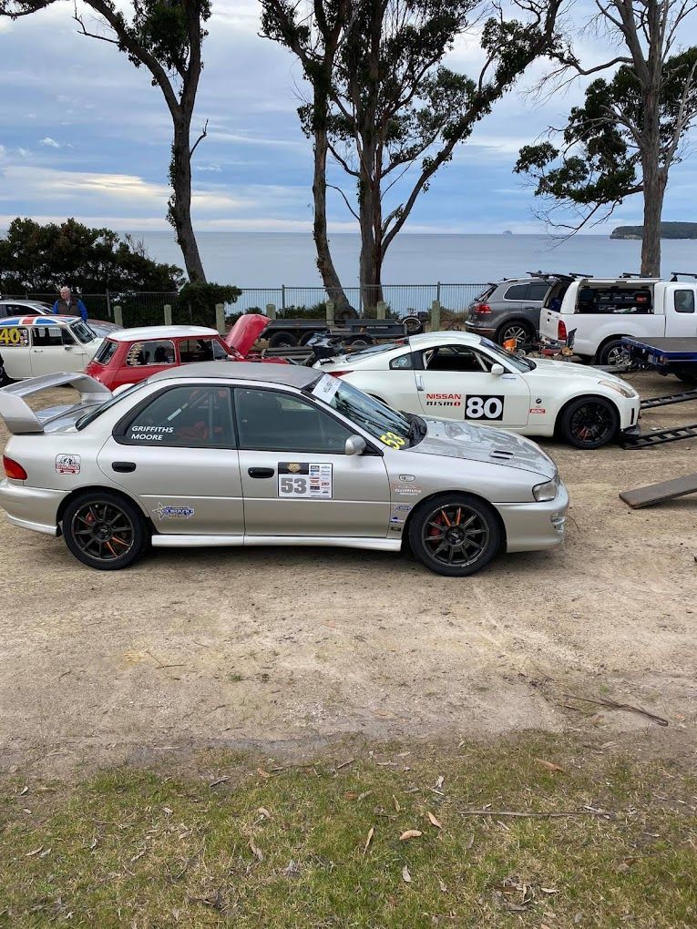 A silver car is parked next to a white car in a parking lot.