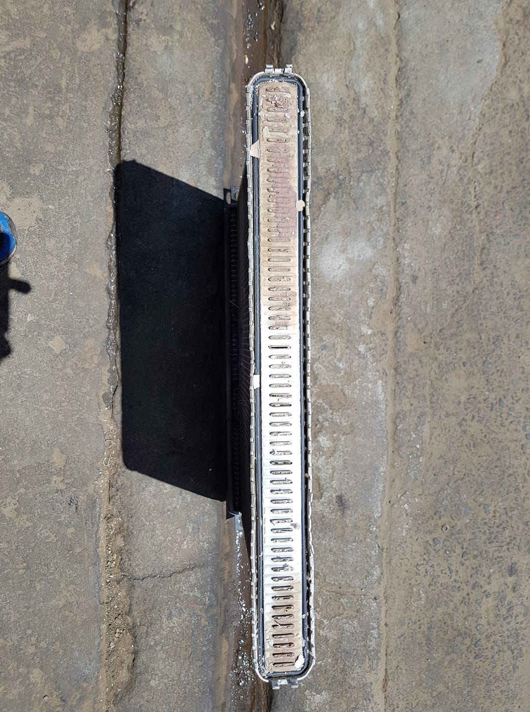 A very long radiator is sitting on a concrete surface.