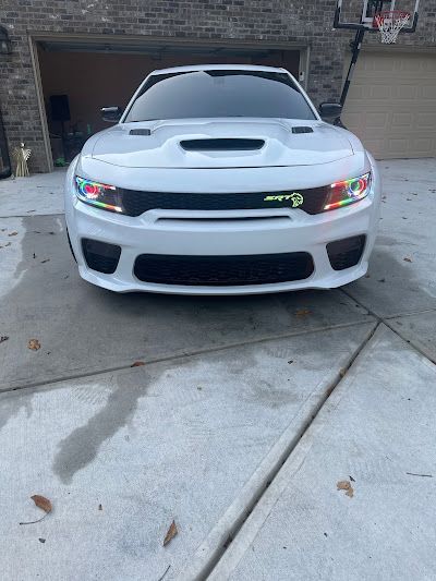 A white dodge charger is parked in front of a garage.
