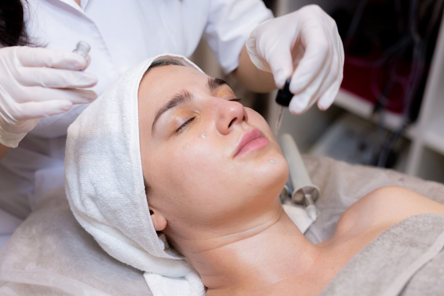 A professional applying serum with a dropper to a person's face during a spa treatment.