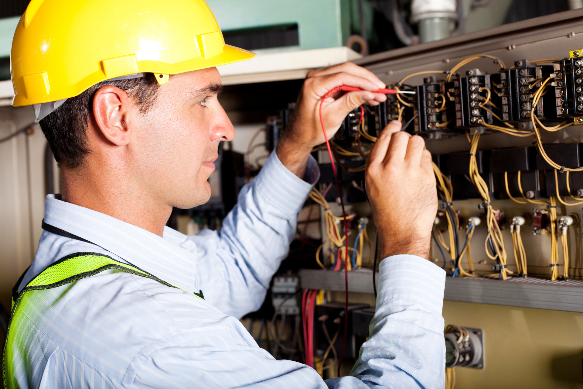 Commercial electrician services technician repairing a circuit board inside a panel box.