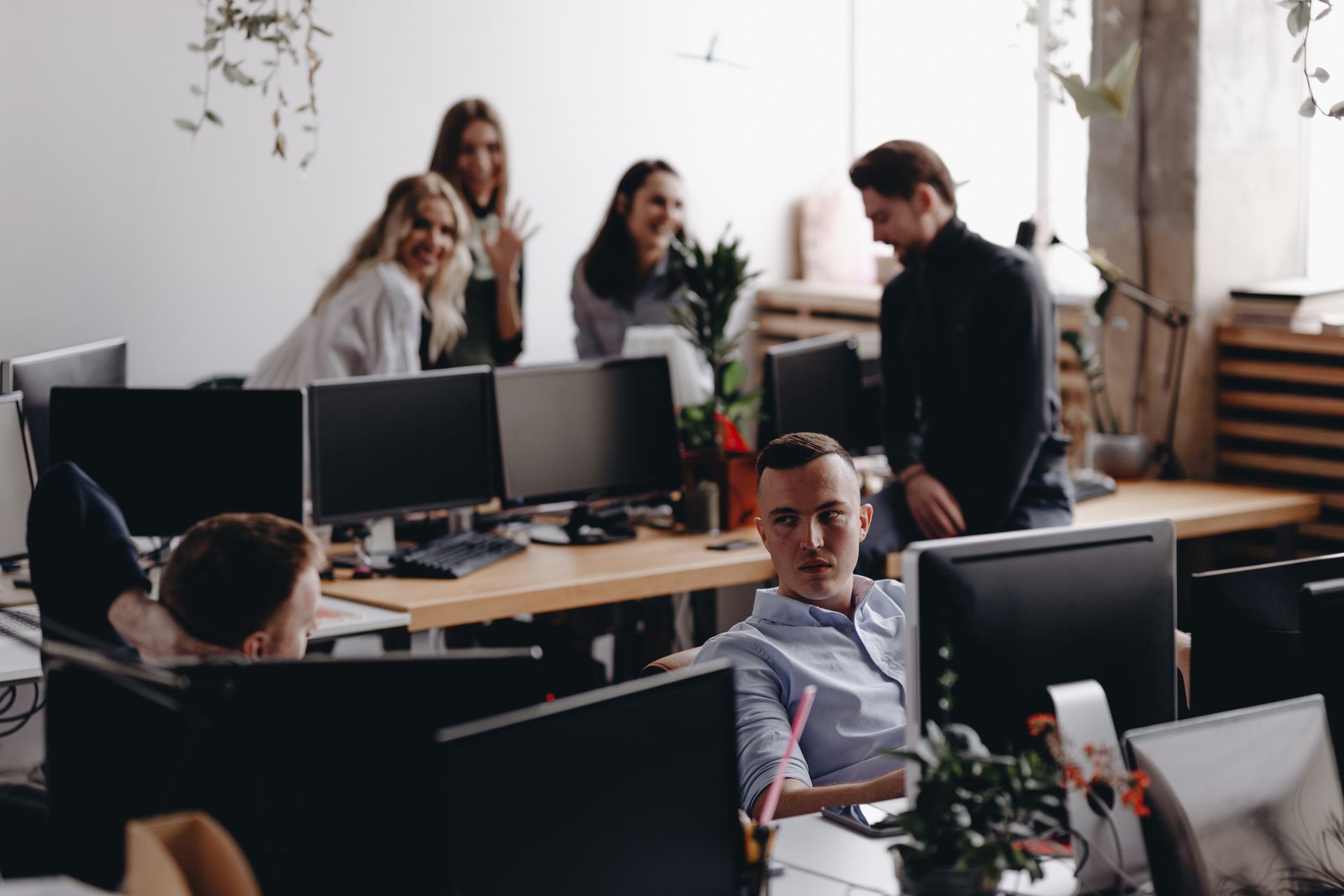 A group of people are sitting at desks in an office talking to each other.