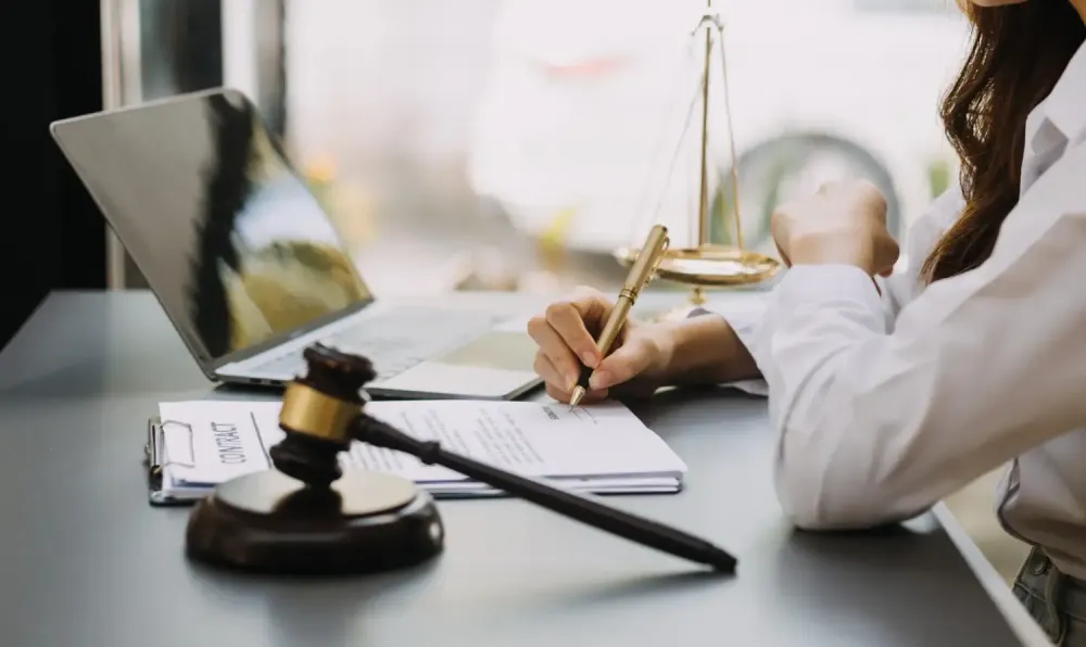 A woman is sitting at a desk with a laptop and a gavel.