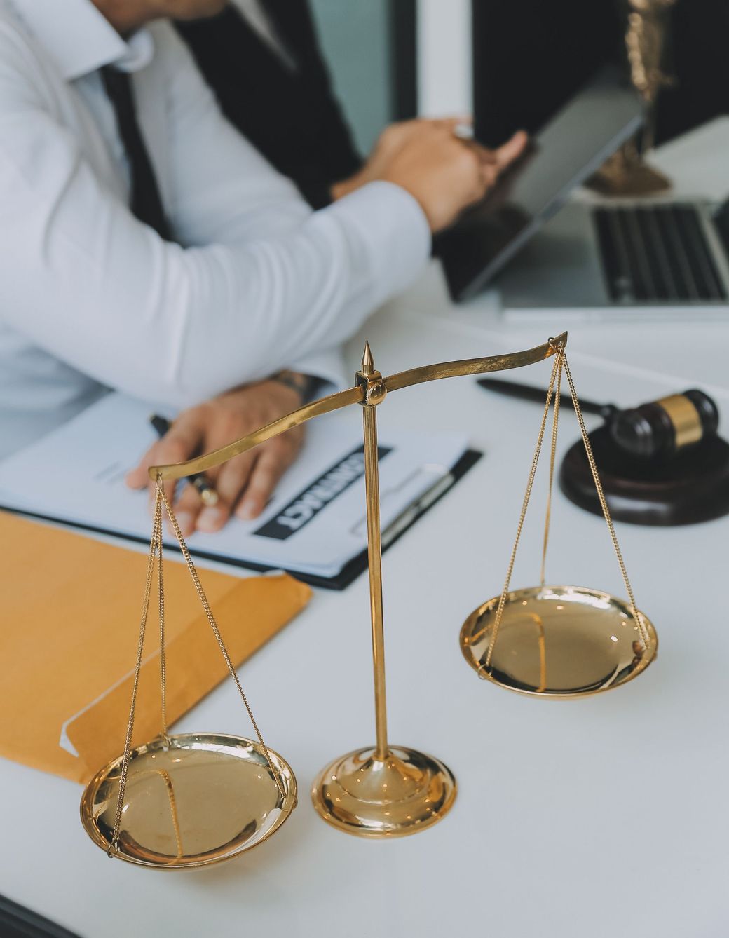 A man is sitting at a desk with a scale of justice and a judge 's gavel.