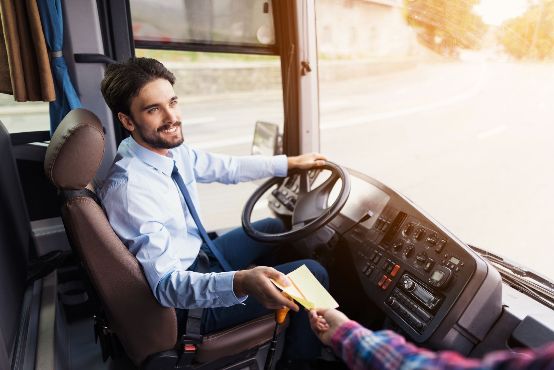 A man is sitting in the driver 's seat of a bus.