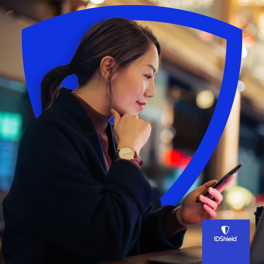 A woman is sitting at a table looking at her phone