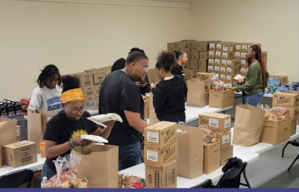 A group of people are standing around tables filled with boxes and bags.