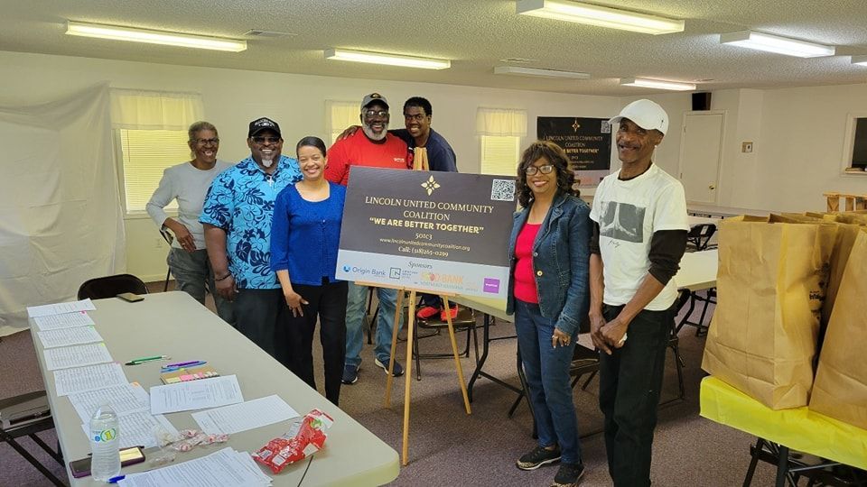 A group of people standing around a table holding a sign.