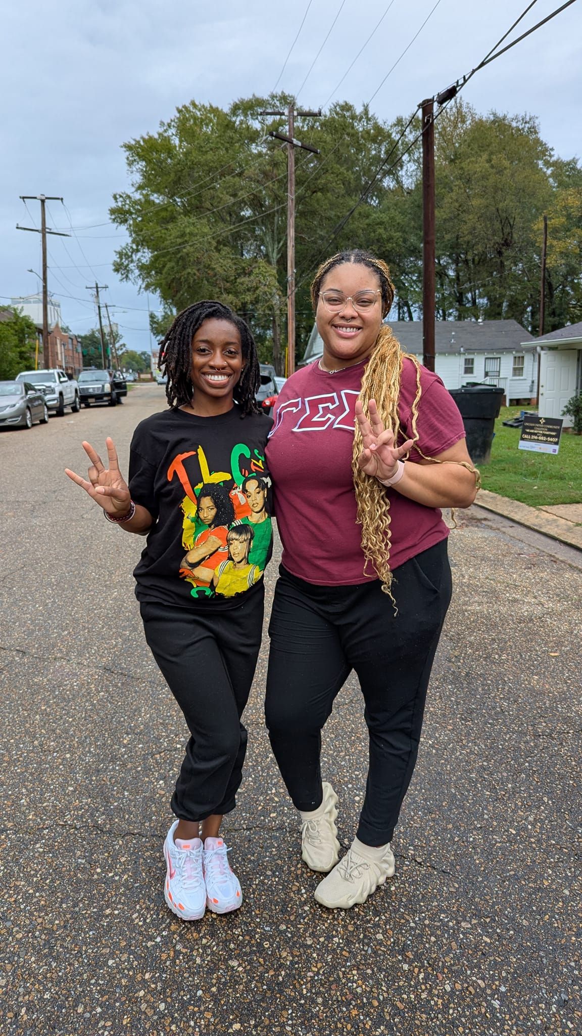 Two women are standing next to each other on a street.