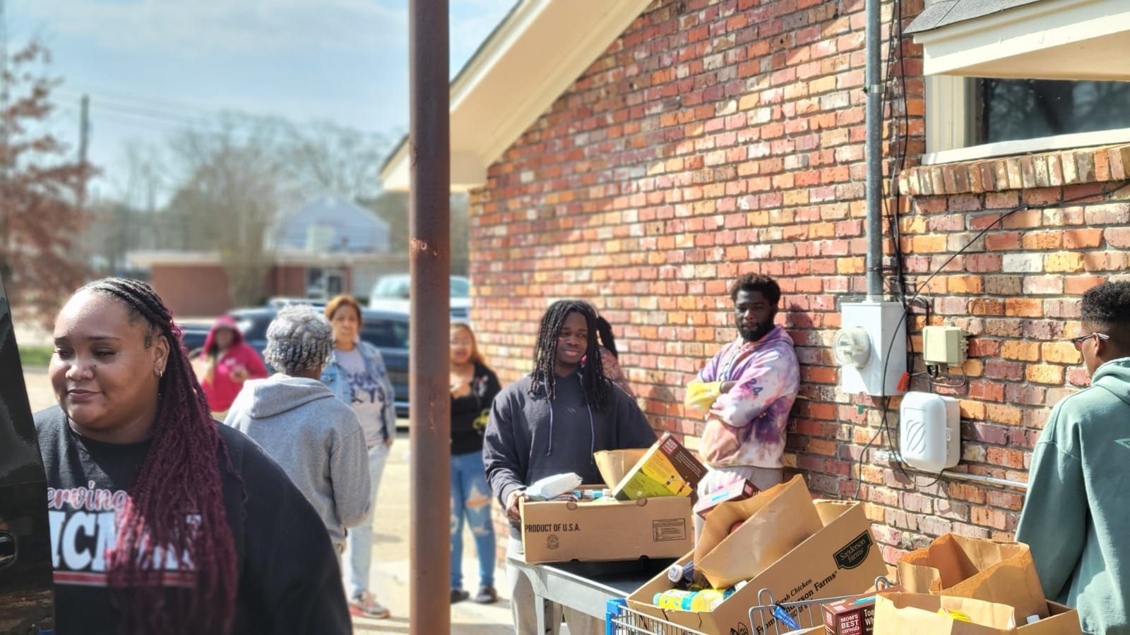 A group of people are standing in front of a brick building.