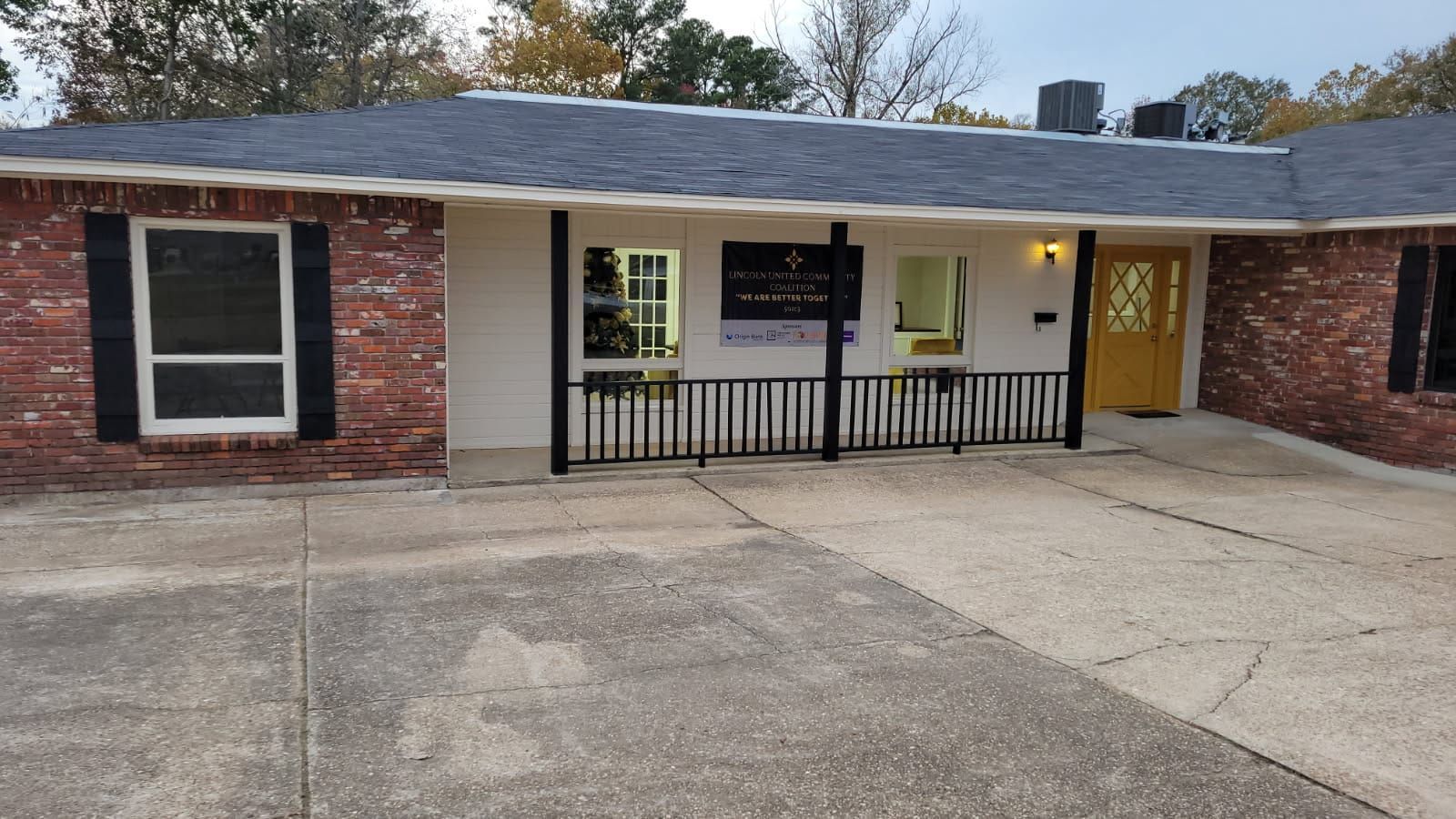 A brick house with a yellow door and black shutters