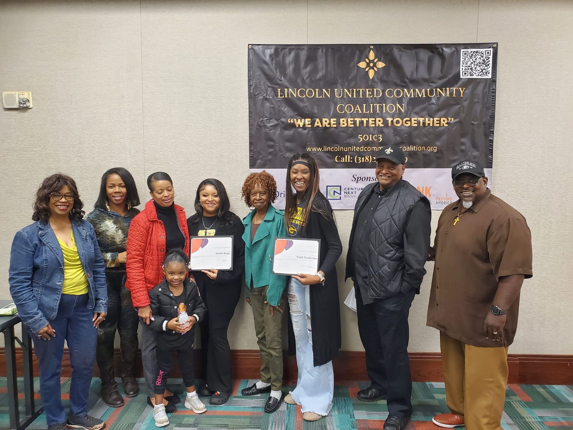 A group of people are posing for a picture in front of a sign that says lincoln united community council.