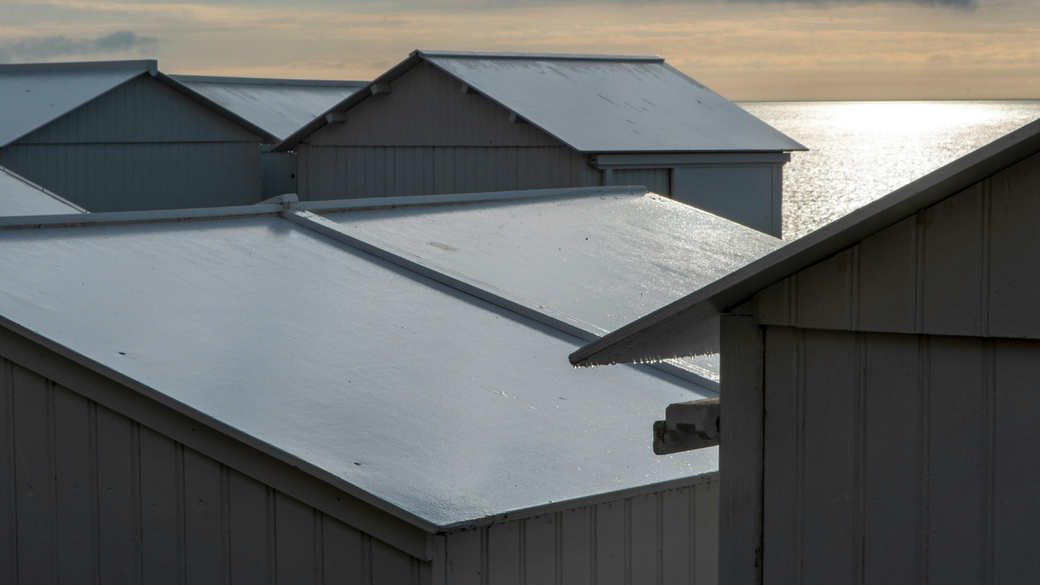 Snow-covered rooftops by the water at dawn