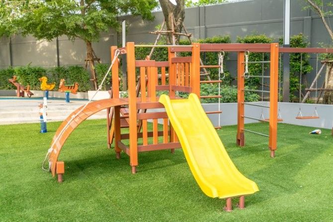 Orange-and-yellow playground slide structure on green artificial grass outdoors