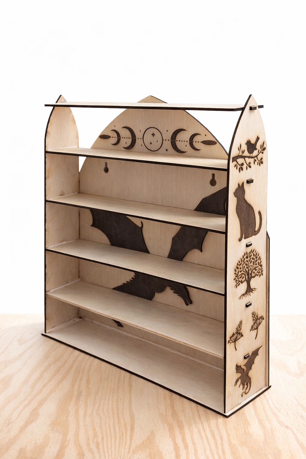 A light-wood, tiered display shelf with a decorative, arched back featuring lunar phases and a dark bat silhouette.