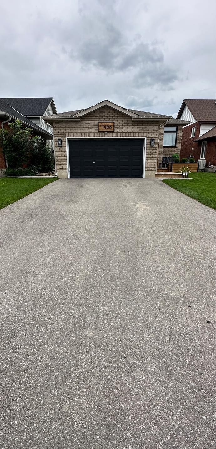 A driveway leading to a house with a black garage door.