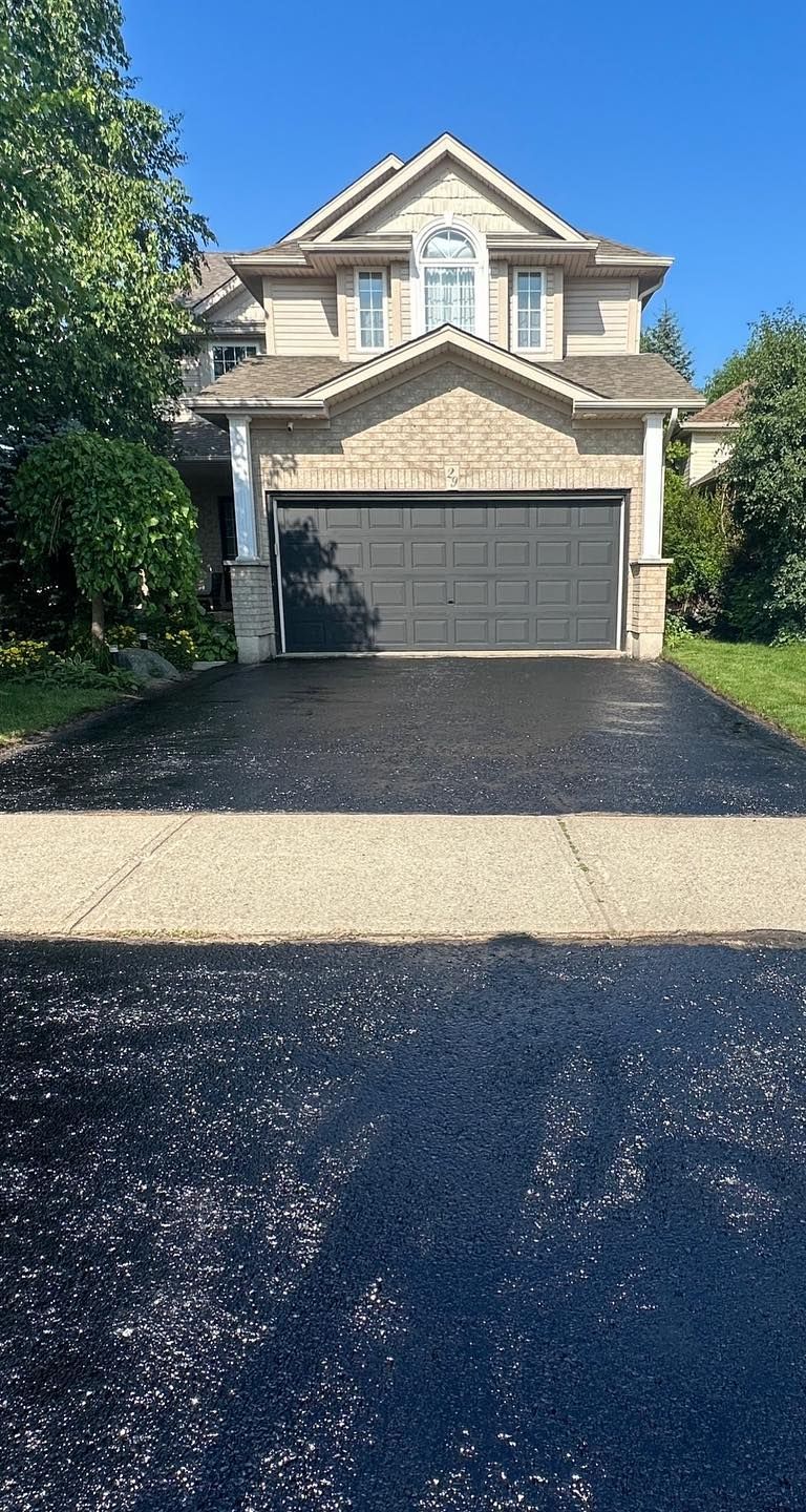 A large house with a black garage door and a black driveway.